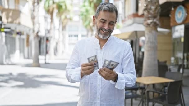 Junger Hispanischer Grauhaariger Mann Lächelt Selbstbewusst Und Zählt Dollar Auf — Stockvideo