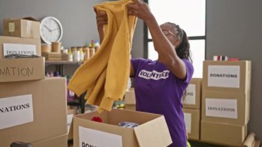 Afro-Amerikalı kadın gönüllü olarak bağış merkezi deposunda kıyafet tasnif ediyor..