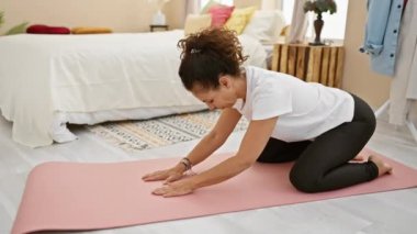 Olgun İspanyol kadın yatak odasında yoga yapıyor. Huzur ve sükuneti somutlaştırıyor..