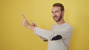 Mutlu orta yaşlı, sakallı, İspanyol bir adam kendinden emin, sarı izole arka plan portresi içinde, ürün reklamı için sıcak gülümsemeler davet ediyor.!