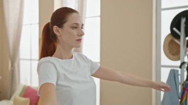 Huzurlu kızıl saçlı bir kadın güneşli bir oturma odasında uzanıyor, sakin ve sağlıklı bir şekilde yayılıyor..