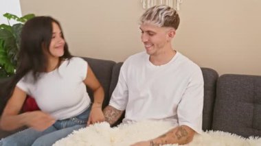 Keyifli bir adam ve kadın, sıcak bir oturma odasında kanepede sarılıyor, sevgi ve birlikteliği çağrıştırıyor..