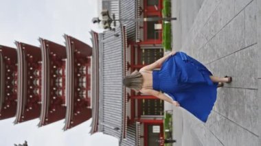 Neşeli İspanyol kadın, Senso ji Tapınağı 'nın Tokyo' daki görkemli mimarisi arasında güzel elbiseler içinde neşeyle dans ediyor. Japonya 'yı gezerken, şehir maceralarında mutluluk saçar..