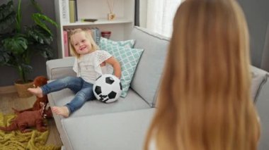 Mutlu Kafkas anne ve kızı kanepede top oynuyor, evde, oturma odasında, aile içinde el çırpıyorlar.