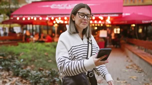 Χαμογελαστή Νεαρή Γυναίκα Χρησιμοποιώντας Smartphone Υπαίθριο Καφέ Ρύθμιση Φωτισμό Βράδυ — Αρχείο Βίντεο