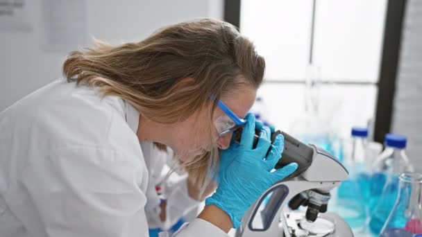坚定的金发女科学家全神贯注地工作着 在实验室用显微镜仔细地工作着 — 图库视频影像