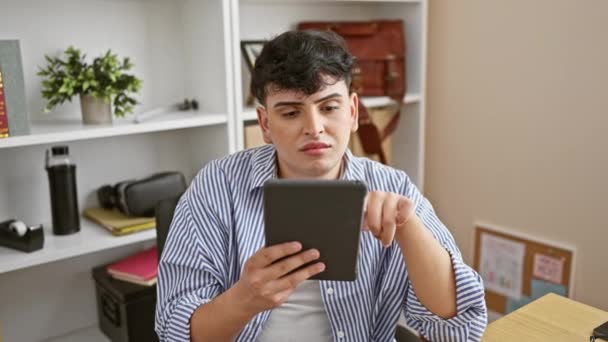 一个穿着条纹衬衫的年轻人正在一间现代化的办公室里小心翼翼地使用平板电脑 — 图库视频影像