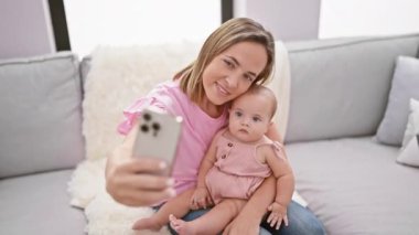 Havalı anne ve tapılası kızı rahat bir selfie çekiyorlar, evde mutlu bir hayat sürüyorlar, sevgi ve güvenle gülümsüyorlar.