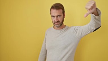 Genç Latin asıllı adam mutsuz ve kızgın görünüyor. Reddedilmiş ve olumsuz bir hareket sergiliyor. Kötü ifade. izole edilmiş sarı arkaplan