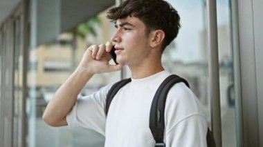 Sırt çantasıyla önemli bir telefon görüşmesi yapmak için akıllı telefonu kullanan sıradan bir İspanyol üniversite öğrencisi. Güneşli şehir kampüsünde durmuş, sohbete dalmış..