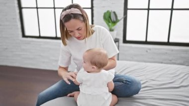 Anne ve kız yatakta oturuyor, birlikte gülüyorlar ve rahat bir yatak odasında rahat kıyafetler giyiyorlar. Sevgi dolu ve neşeli aile ifadelerinin bir göstergesi.