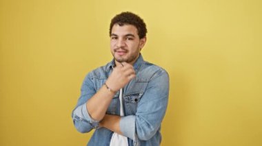 Stresli genç bir Arap endişeyle tırnak yiyor, sarı arka planda tek başına duruyor, gergin görünüyor, sorunlarla boğuşuyor..