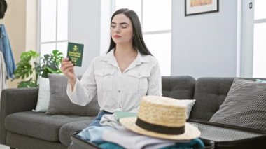 Neşeli, genç, İspanyol bir kadın. Gülümsüyor, güzel bir şekilde elinde Suudi Arabistan pasaportuyla evinde rahat bir şekilde oturuyor.!