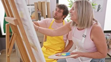 İki kendine güvenen sanatçı, erkek ve kadın, kapalı alan sanat stüdyosunda resim yaparken, birlikte resim çizmekten zevk alırlar.