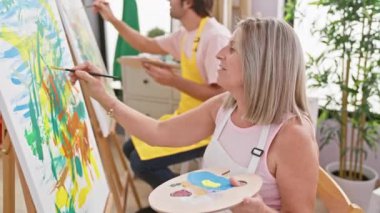 İki kendine güvenen sanatçı, erkek ve kadın, kapalı alan sanat stüdyosunda resim yaparken, birlikte resim çizmekten zevk alırlar.