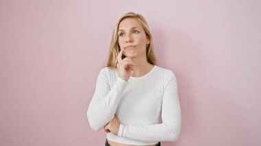 Düşünceli, genç, sarışın bir kadın bir soru üzerine kafa yoruyor, çenesi beşik gibi elinde, dalgın yüzünde bir gülümseme oynuyor. İfadesinde belirsizlik var. Pembe izole bir arka planda muğlak bir bulmaca..