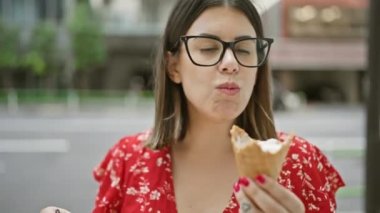 Neşeli, güzel, bardaklı İspanyol bir kadın Tokyo 'nun canlı caddesinde lezzetli bir dondurmanın tadını çıkarıyor. Şehrin şehir mimarisini kucaklıyor. Eğlence dolu yaz tatili gezisi boyunca.