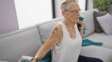 Isınmak isteyen yaşlı gri saçlı kadın, battaniyeye sarılmış, dondurucu soğukta, evinde grip belirtileri gösteriyor.