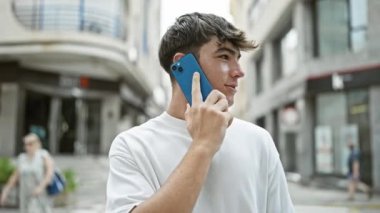Genç İspanyol bir adam, Sunlit Caddesi 'nde akıllı telefonuyla ciddi bir konuşma yapıyor. Yoğun bir konsantrasyon gösterirken rahat ve havalı bir yaşam tarzının bir örneği.