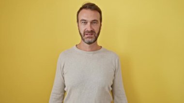 Neşeli orta yaşlı İspanyol bir adam ayakta ve başarılı bir galibiyeti kutluyor, kollarını kaldırıp evet diyor, hepsi izole edilmiş sarı bir arka plana karşı.