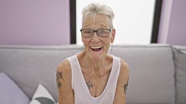 Fröhliche Grauhaarige Seniorin Findet Freude Bequem Auf Ihrem Gemütlichen Wohnzimmersofa — Stockvideo