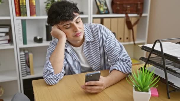 Young Man Striped Shirt Looks Bored Smartphone Modern Office — Stock Video