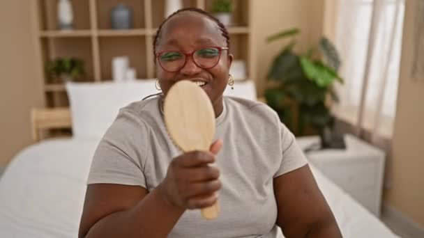 自信的非洲裔美国女人欢快地唱着她的晨曲 在舒适的床上用刷子当话筒 — 图库视频影像