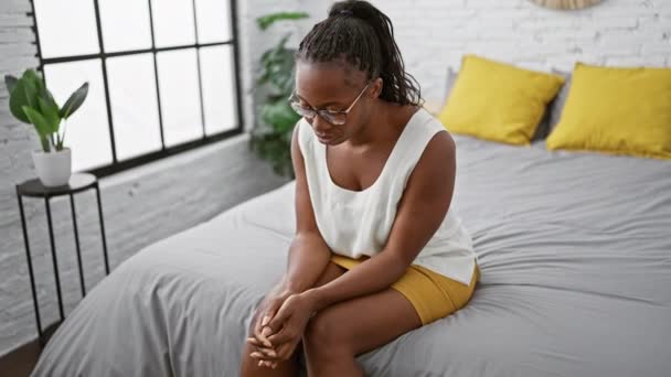 Mujer Afroamericana Reflexiva Sentada Cama Interior Moderno Dormitorio Con Gafas — Vídeo de stock