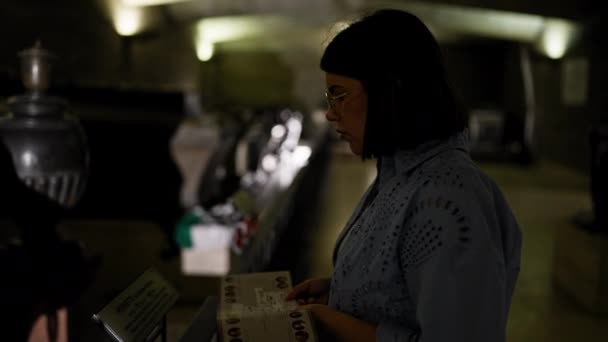 若い美しいヒスパニック系女性がウィーンのインペリアル クリプトで暗い読書パンフレットを訪問 — ストック動画