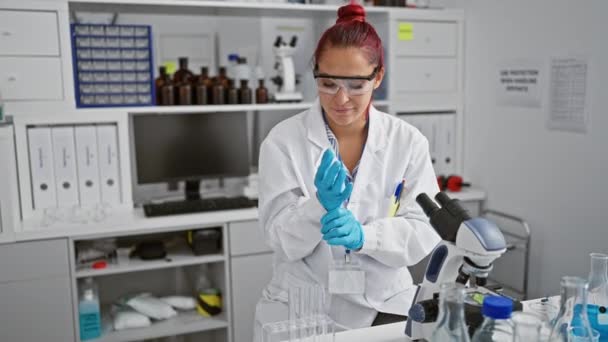 優秀な若い赤毛の女性科学者は医学研究に集まり テスト チューブの液体を細心の注意深く測定しましたり 頑丈な実験室の忙しい中心で手袋を — ストック動画