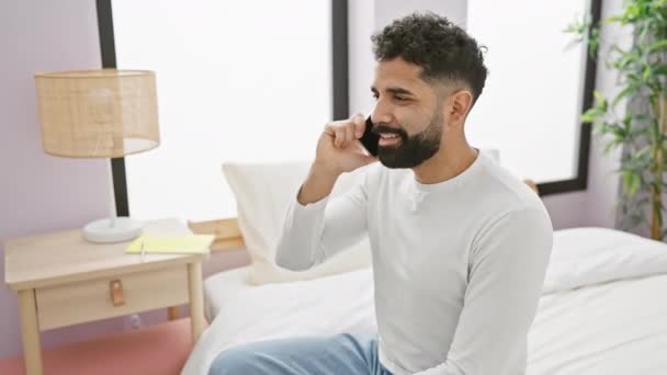 Улыбающийся Молодой Бородатый Мужчина Разговаривает Телефону Современной Спальне Изображая Случайный — стоковое видео