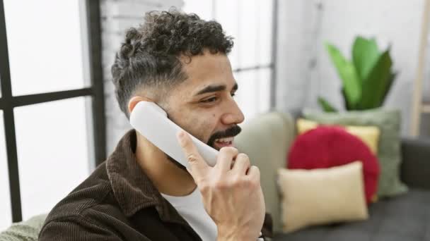 一个留着胡子的年轻人在舒适 现代的家中用固定电话交谈 引起了一种随意交流的感觉 — 图库视频影像