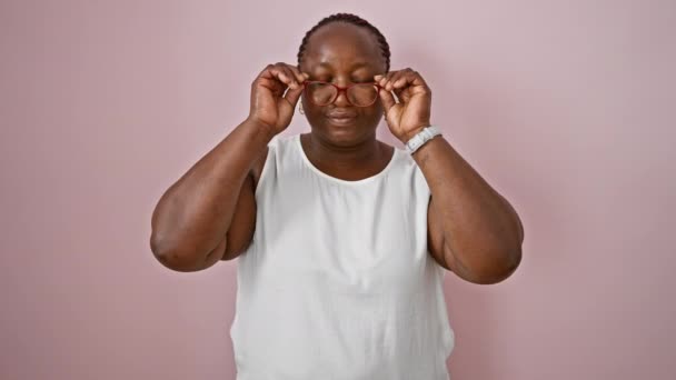 自信を持ったアフリカ系アメリカ人女性がメガネを外し 明るいピンクの孤立した背景に微笑む — ストック動画