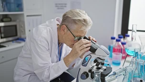 グレイ髪の女性科学者は 実験室で顕微鏡下のサンプルを分析しながら動揺している — ストック動画