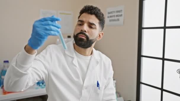 Jovem Hispânico Com Barba Examina Tubo Ensaio Ambiente Laboratório Brilhante — Vídeo de Stock