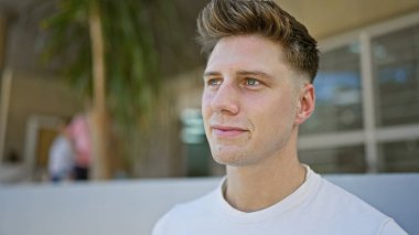 Genç, yakışıklı, beyaz, sakin ama ciddi bir yüz ifadesi sergiliyor, açık havada güneşli bir havada dikilirken yan tarafa bakıyor. Sokak modası şehir ve havalı yaşam tarzını gözler önüne seriyor.