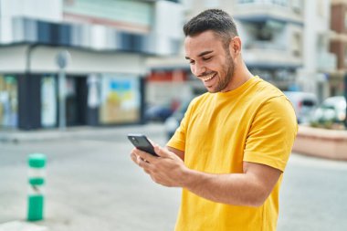 Sokakta akıllı telefon kullanan, kendine güvenen genç bir İspanyol.