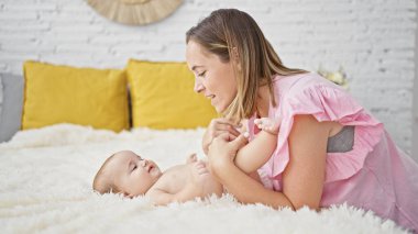 Anne yatakta oturuyor ve kızı yatak odasında öpüşüyor.