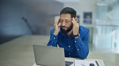 Genç İspanyol iş adamı ofiste çalışırken baş ağrısı çekiyor.