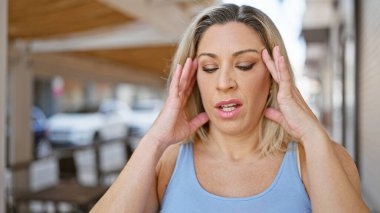 Sokakta baş ağrısı çeken genç sarışın kadın.