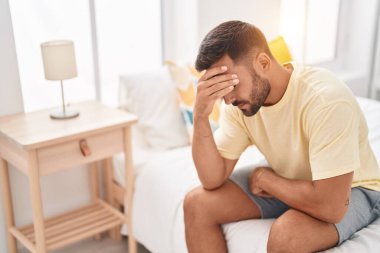 Genç İspanyol adam yatakta otururken stresli.