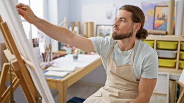 Sanat stüdyosunda resim çizen genç bir İspanyol.