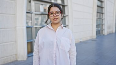 Günlük giysiler içinde genç bir İspanyol kadın. Şehir sokaklarında güven içinde poz veriyor. Günlük güzelliği ve basitliği somutlaştırıyor..