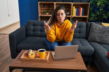 Young beautiful plus size woman having breakfast doing yoga exercise at home