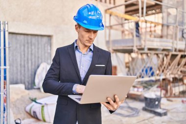 Young man architect using laptop at street