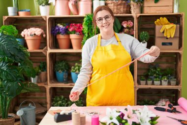 Çiçekçide kendine güvenen, kendine güvenen, genç ve iri kadın bir çiçekçi.