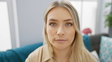 Güzel, beyaz tenli, sarışın bir kadın evinde, evinde, kapalı bir yerde, oturma odasında, yetişkin hayatının portresini çizerken ciddi bir ifadeyi canlandırıyor..