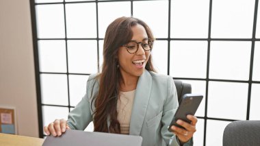 Işıl ışıl genç İspanyol kadın başarılı bir iş adamı olarak işinden zevk alıyor, kendine güvenen, mesaj atan ve gülümseyen, hepsi zarif bir ofis içinde otururken.