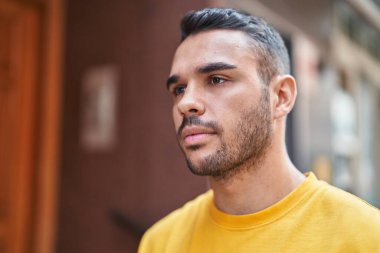 Latin kökenli genç adam ciddi bir ifadeyle sokağa bakıyor.