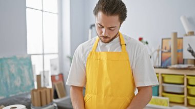Sanat stüdyosunda ciddi bir yüzle duran genç İspanyol sanatçı.